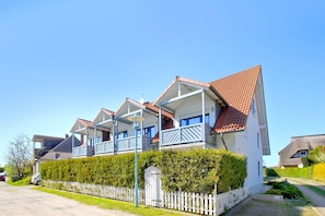 A row of white houses with red roofs and blue balconies, surrounded by a white picket fence and greenery. - Cozy vacation apartment near the harbor - FeWos am Hochzeitsberg FeWo 17 - FeWos (Breege)