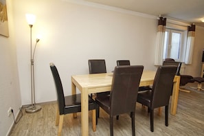 Ein Essbereich mit einem Holztisch, sechs Stühlen, einer Stehlampe und einem Fenster mit Vorhängen.