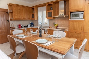 A modern kitchen with wooden cabinets, a dining table set for four, and a microwave above the counter.