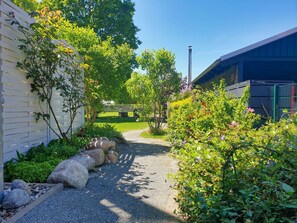 A gravel pathway leading to a building with a white exterior and a green roof. - Modern Apartment No. 4 with balcony, in-house sauna, and garden - Ferienwohnungen am Wald - (Glowe)