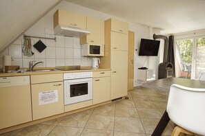 A modern kitchen with a built-in oven, a microwave, and a gas stove. There is a sign on the wall indicating a recycling bin.