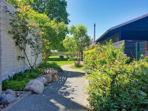 A gravel pathway leading to a building with a white exterior and a green roof.