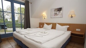 A double bed with white linens and towels, two bedside lamps, a wooden headboard, and a view through a large window. - Close to the famous cape, beautiful sandy beach - Ferienresidenz Kap Arkona FeWo 06 - (Putgarten)