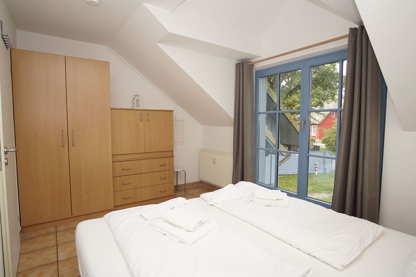 Ein Schlafzimmer mit Bett, Kleiderschrank und einem Fenster mit Vorhängen.