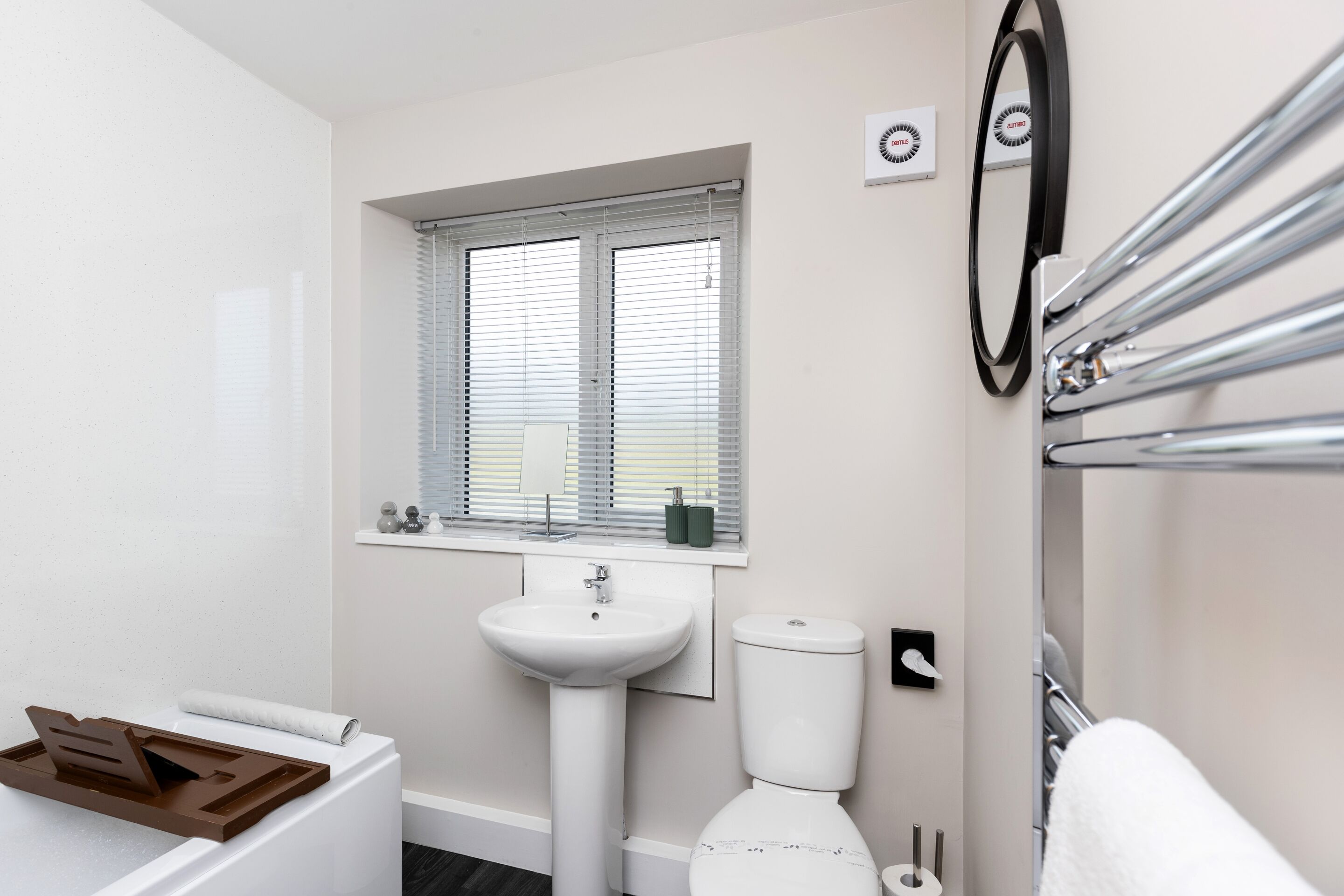 A bathroom with a sink, toilet, and window with blinds.