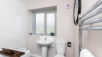 A bathroom with a sink, toilet, and window with blinds.