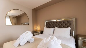 Habitación de hotel con una cama grande, un espejo redondo, una mesita de noche con lámpara y dos toallas con la palabra 'slippers'.