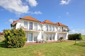 A two-story house with a red-tiled roof, large windows, and a balcony. - Lots of nature, idyllic surroundings, quiet location - Ferienpark Neddesitz FeWo 48 - (Sagard)