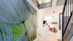 A modern interior with a staircase, a dining area, and a large abstract mural.