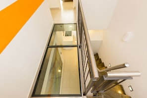 Et moderne interiør med en glas elevatoraksel, metalgelændere og et flisegulv.