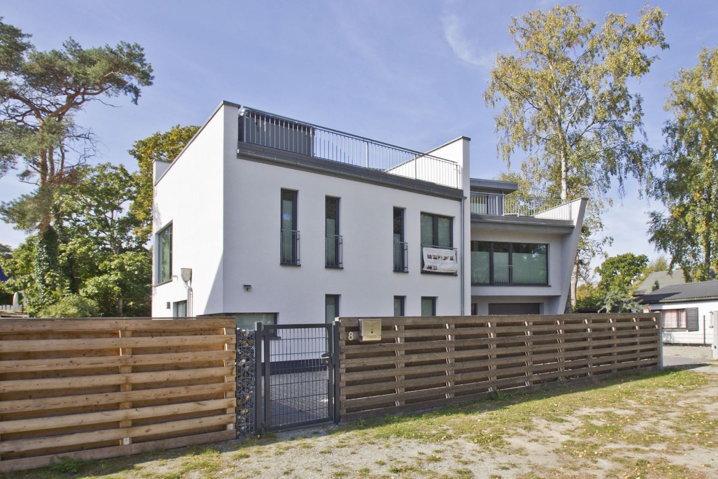 A modern two-story building with a white facade, large windows, and a balcony.