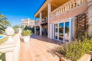 A two-story building with a covered patio, a swimming pool, and a view of a residential area. - House in Alcudia Aran Berna with swimming pool (Alcúdia)