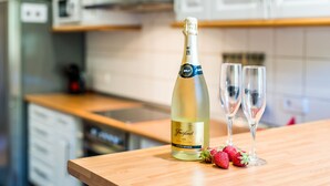 A bottle of Freixenet cava wine, two empty wine glasses, and fresh strawberries on a wooden countertop in a kitchen. - House in Alcudia Aran Berna with swimming pool (Alcúdia)