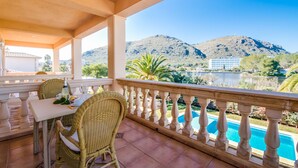 A balcony with a table and chairs overlooking a pool and mountains. - House in Alcudia Aran Berna with swimming pool (Alcúdia)
