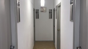 A narrow hallway with doors labeled 01 to 06, a light fixture, and a small decorative item on the wall. - Giannis Rooms (Chora Sfakion)