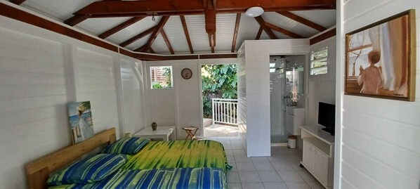 Un dormitorio con cama, televisor, reloj y ventana.