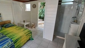 Une chambre à coucher comprenant un lit, une petite table, une chaise, un téléviseur et une salle de bain avec douche.