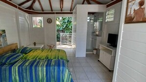 Une chambre avec un lit, une télévision, une petite table et un balcon.