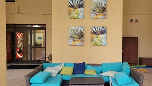 An outdoor seating area with a blue sofa and cushions, a small table, and four wall-mounted artworks. - Amazing Beachview Close to Downtown Entertainment (Biloxi)