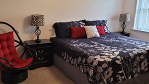 A bedroom with a bed, two nightstands, a red chair, and two lamps. - Amazing Beachview Close to Downtown Entertainment (Biloxi)