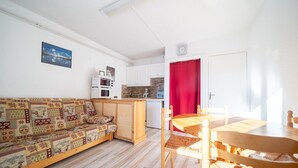 Un espace de vie compact comprenant un canapé, une table à manger et un coin cuisine.