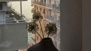 A vase with flowers on a table by a window overlooking a cityscape.