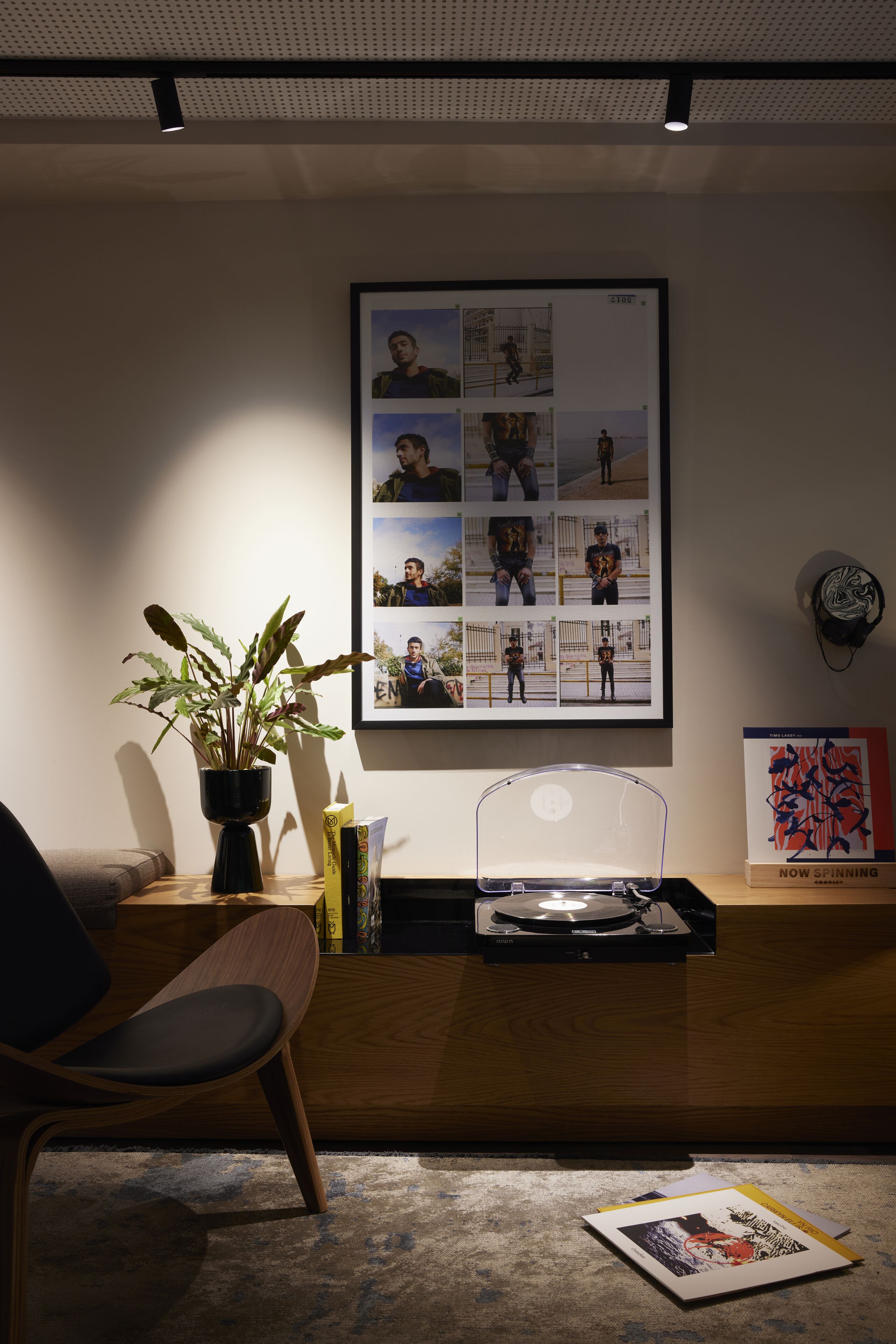 Een moderne kantoorruimte met een houten bureau, een potplant, een lijst met foto's en een platenspeler.