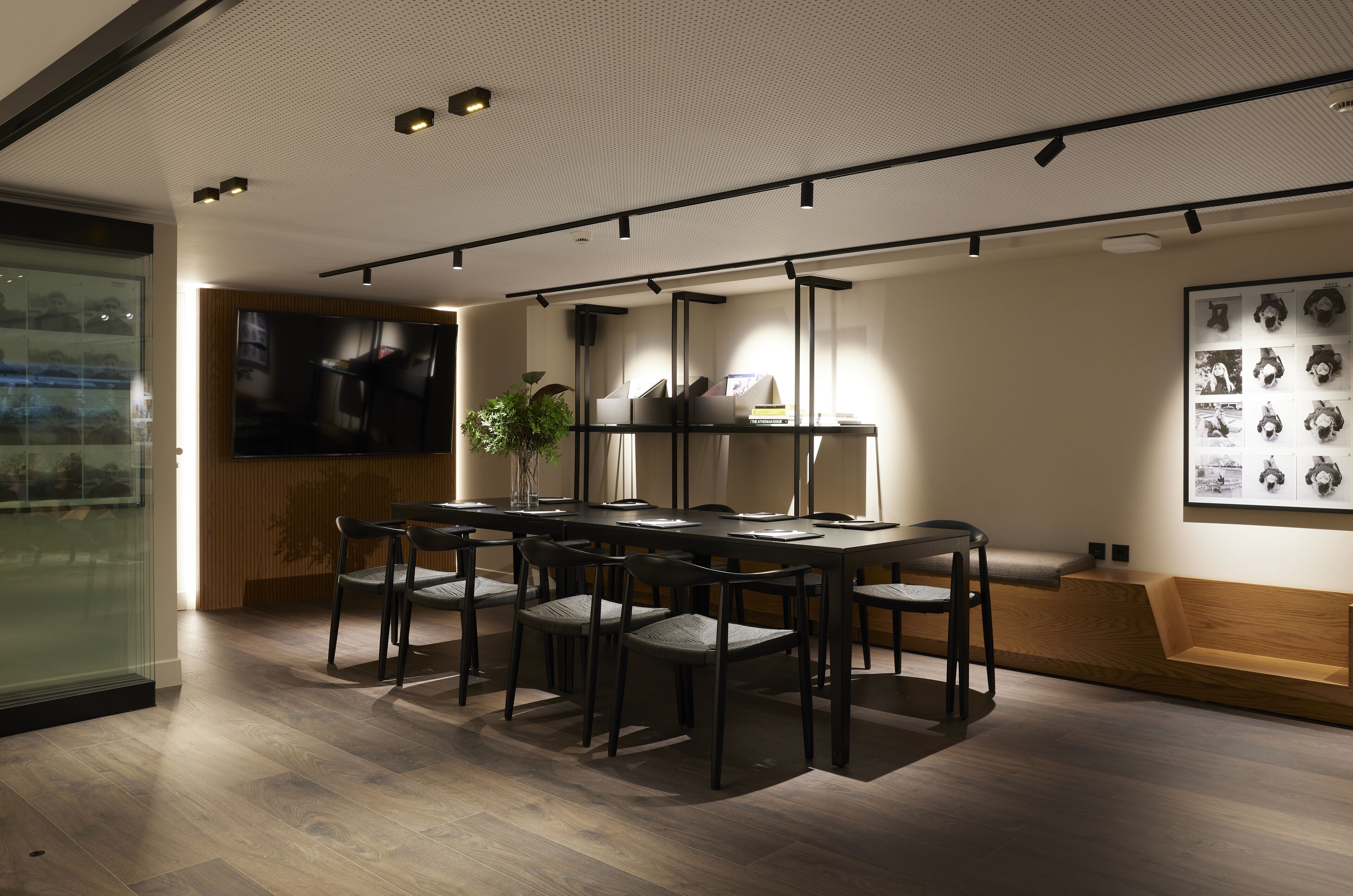 A modern dining area with a long table, multiple chairs, and a plant centerpiece.