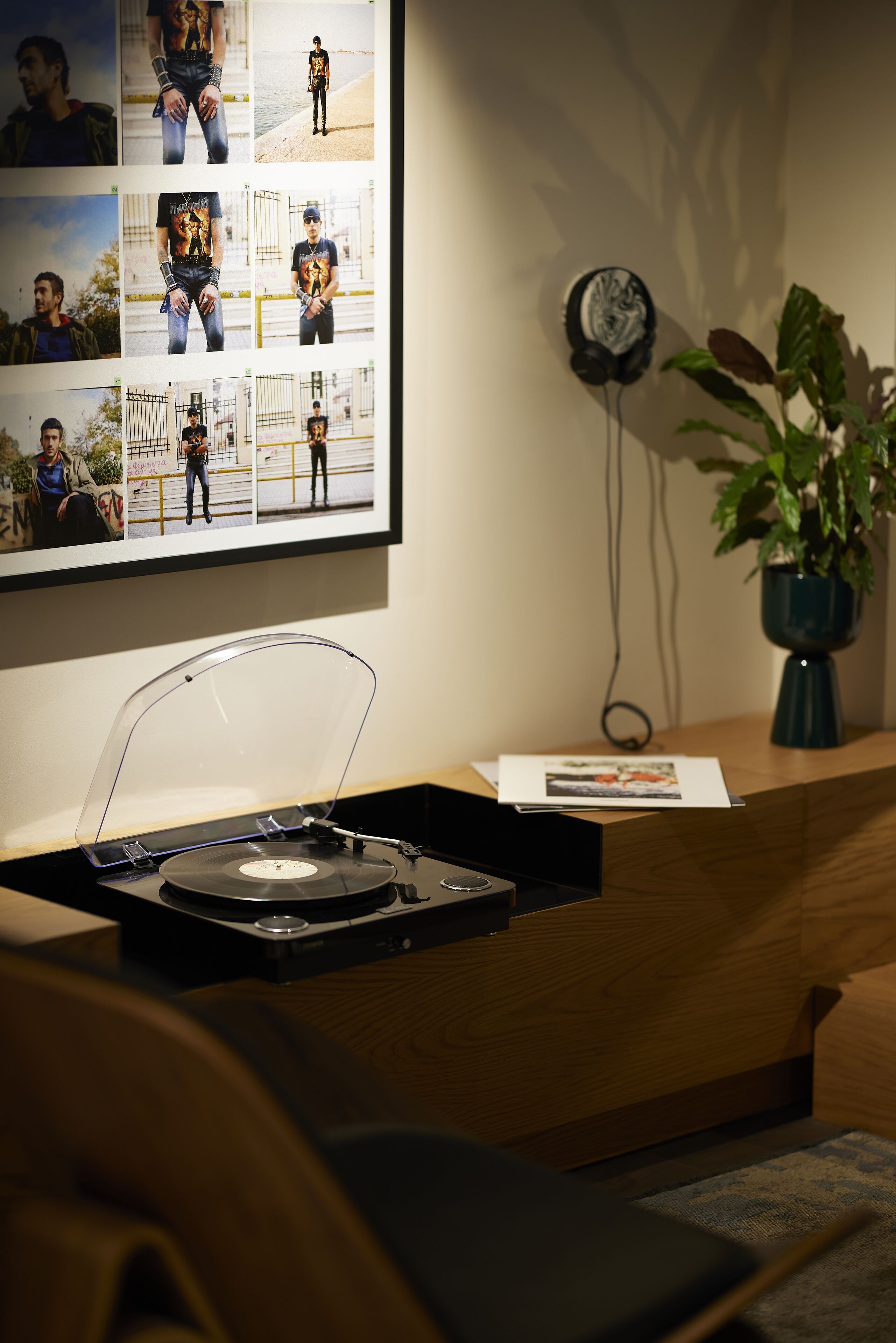 Un mostrador de recepción de madera con un tocadiscos, un collage enmarcado de fotos, un reloj y una planta en maceta.