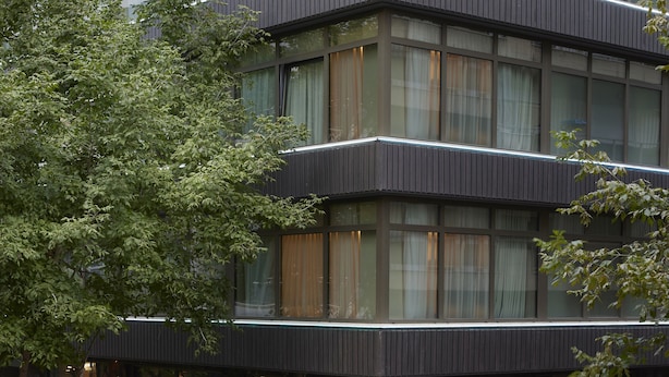 A modern multi-story building with large windows and a covered outdoor area.