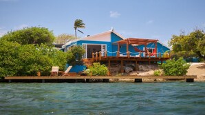 Une maison construite sur pilotis au-dessus de l’eau, dotée d’une terrasse en bois et d’un espace abrité.