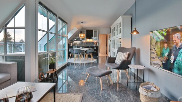 A modern interior with a dining area, kitchen, and large windows.