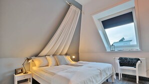 A bedroom with a bed, bedside tables, a window, and a chair.