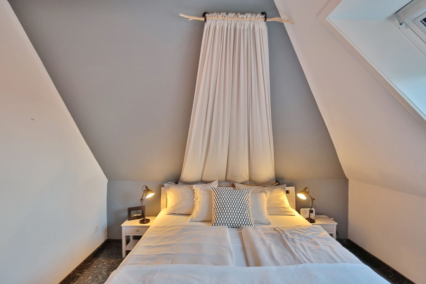 Una camera da letto con soffitto alto e una grande finestra.