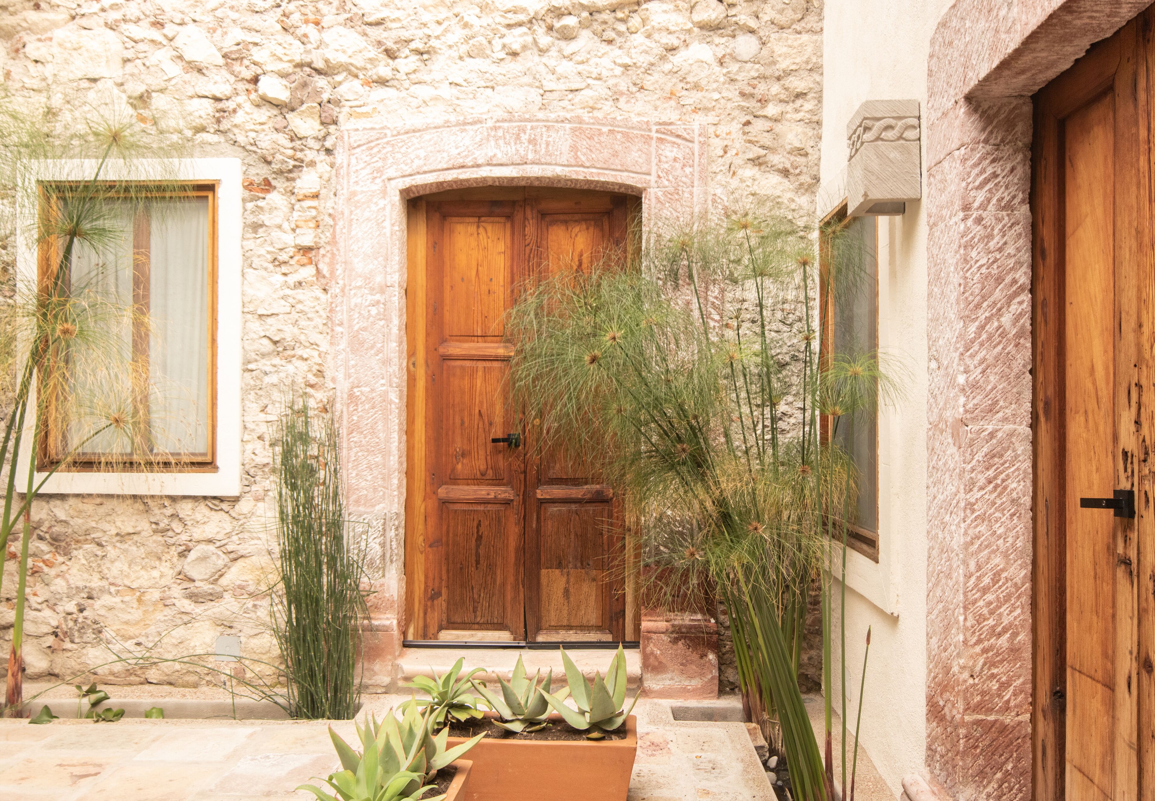 A stone building with a wooden door and potted plants.