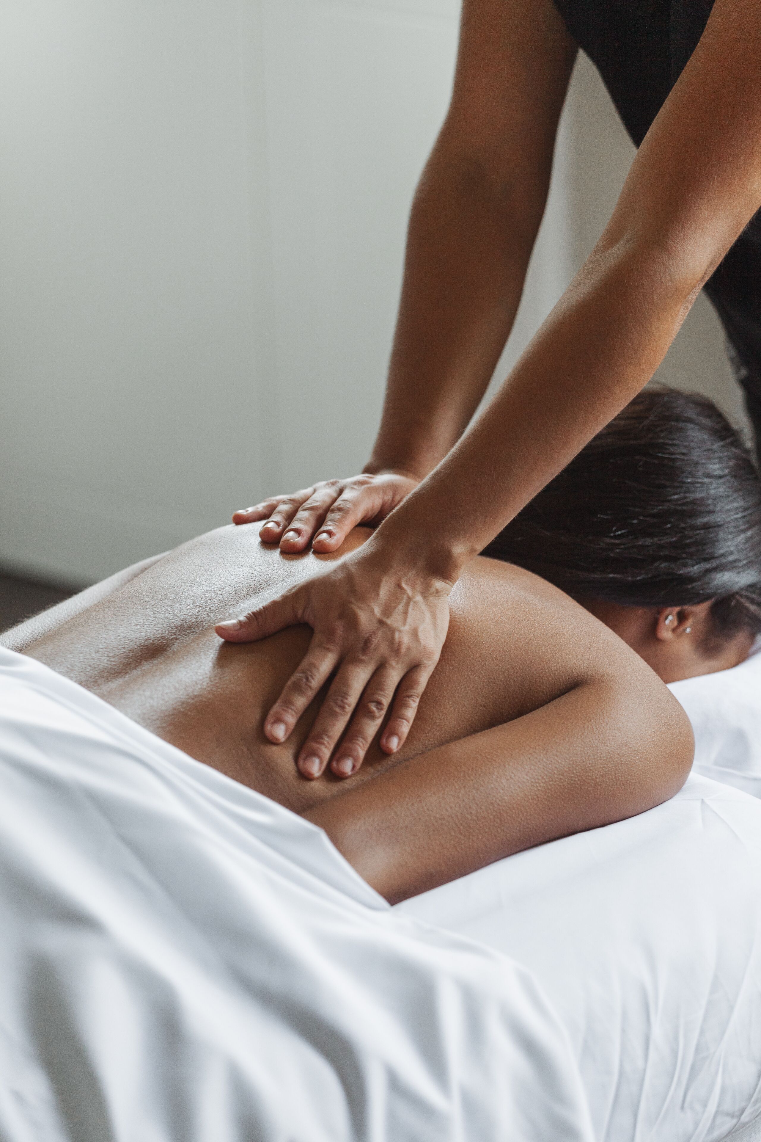 Iemand ontvangt een rugmassage in een kamer met witte muren en een bed.