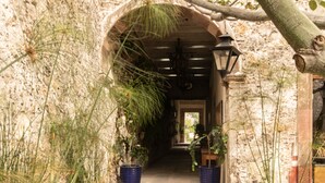 Una entrada de piedra en arco con plantas en macetas a ambos lados, que conduce a un sendero.