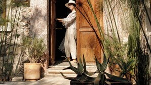 Un edificio de piedra con puerta de madera, plantas en macetas y una ventana pequeña.