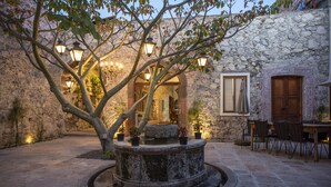 Un patio con una fuente de piedra, plantas en macetas y asientos al aire libre.