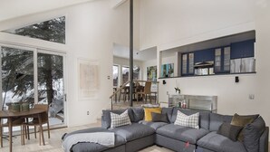 Een moderne woonkamer met een grijze hoekbank, een ronde salontafel en een eethoek met een houten tafel en stoelen.