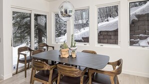 Een eetgedeelte met een donkere tafel, houten stoelen en een grote spiegel erboven.
