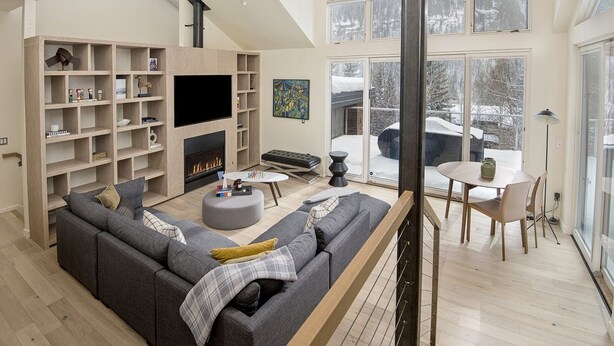 Een moderne woonkamer met een open haard, een grote televisie en een gezellige zithoek.