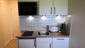 Eine kleine Küche mit weißen Schränken, einer eingebauten Mikrowelle, einem Toaster und einem Spülbecken.