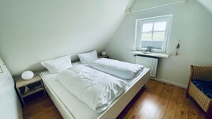 Une chambre à coucher avec un lit, une table de chevet, une fenêtre et un radiateur.