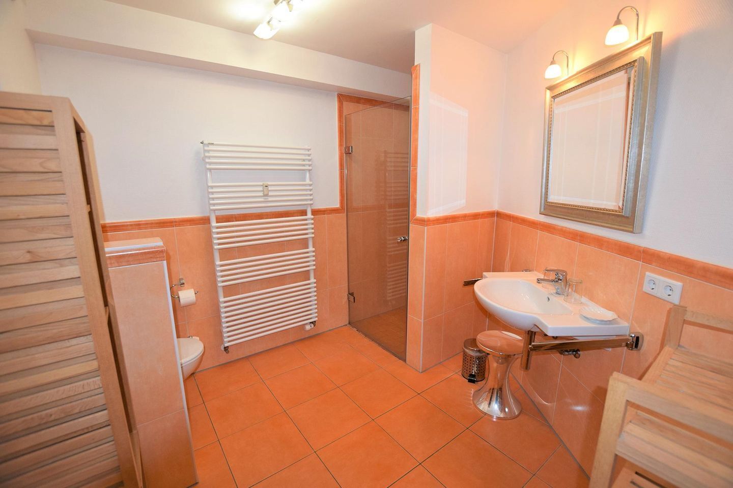 A bathroom with a toilet, sink, shower, and a towel rack.