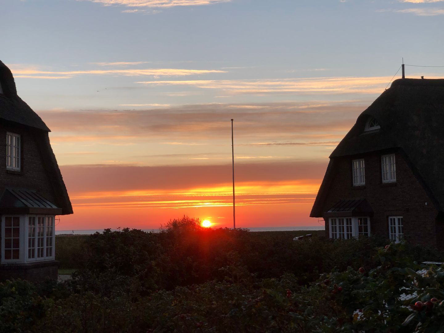 A sunset over a village with traditional houses and a clear sky.