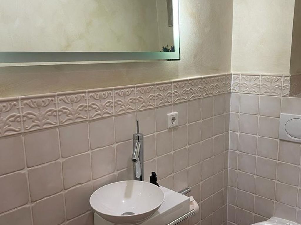 A bathroom with a white sink, a mirror, and a toilet.