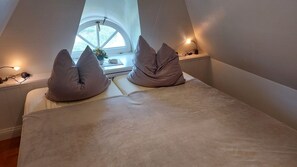 A bedroom with a bed, two pillows, a window, and bedside lamps. - Reethüs am Watt App.4B - Reethüs am Watt (Sylt)
