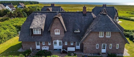 Et stort, tosset hus med en høj taghældning, flere skorstene og en velholdt græsplæne.