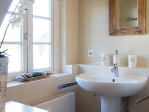 A bathroom with a white sink, a window with a towel rack, and a mirror above the sink. - Söl`ring Hüs "Nautica" SO/22 - Söl'ring Hüs (Sylt)